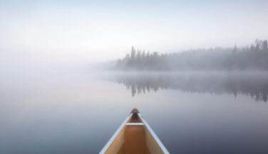 Bow of a canoe on a misty lake in the Boundary Waters
